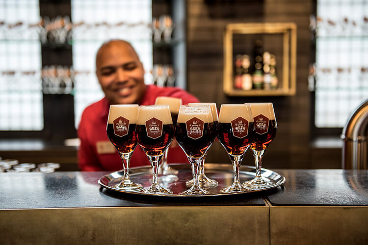 The bartender has a tray of beers ready for visitors at Bruges Beer Experience