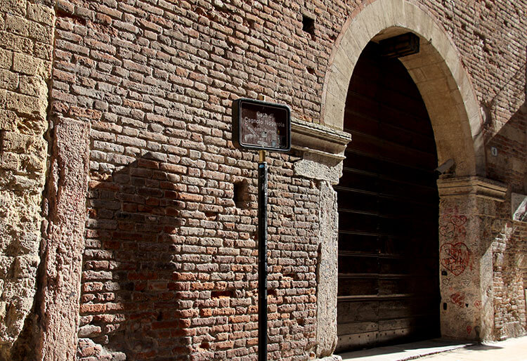 A small sign marks Romeo's house and is next to be a big arched double doorway permanently closed off to the public in Verona