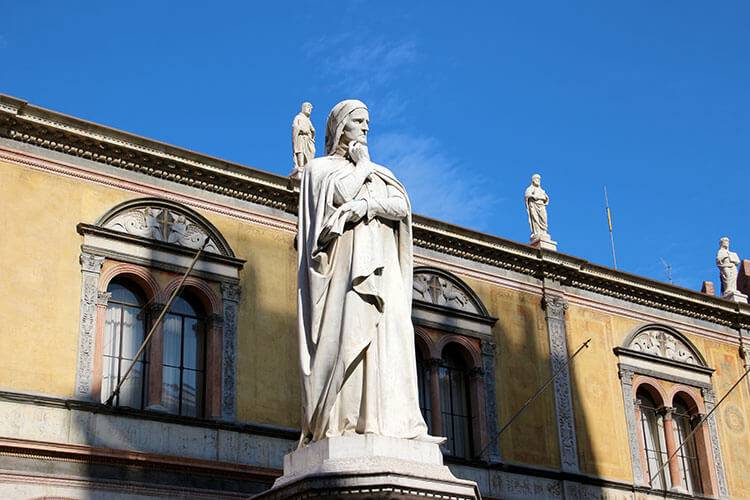A statue of Dante, with one hand raised to his face as he is in deep thought, stands on Piazza dei Signori in Verona