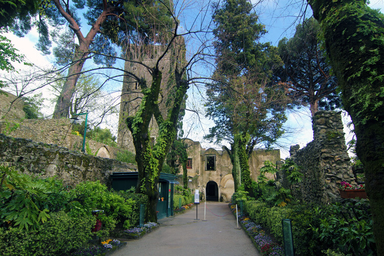 Walking in the garden of Villa Rufolo down a path between Cyprus trees