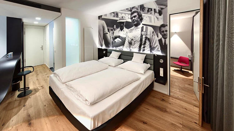 The V6 double room with double bed and a black and white racing photo on the wall at the V8 Hotel Motorworld Stuttgart