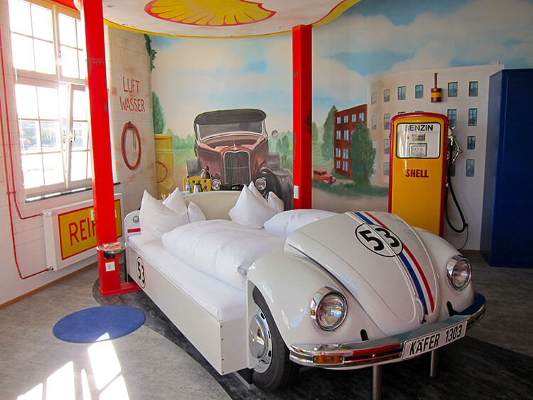 Gas Stationed themed room with a VW Bug Herbie bed, a gas station mural painted on the walls and a gas pump in the room at the V8 Hotel Motorworld Stuttgart