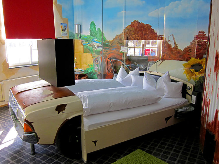 The Nostalgia room with South West US murals on the walls, a junked car as a bed and other scraps turned in to furniture at the V8 Hotel Motorworld Stuttgart