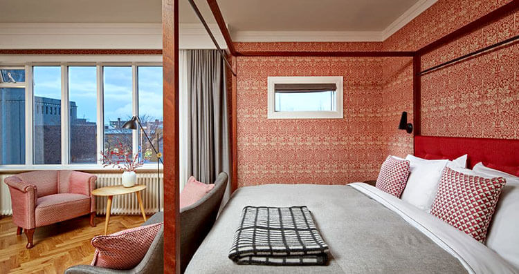 A king room with a canopy-style bed that has Icelandic linens in shades of gray and burdandy at Canopy by Hilton Reykjavik City Centre