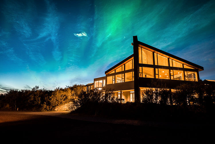 Northen Lights light up the sky behind the glass Hotel Husafell