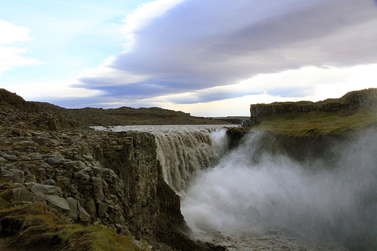 Dettifoss waterfall spills over a ledge creating a powerful spray