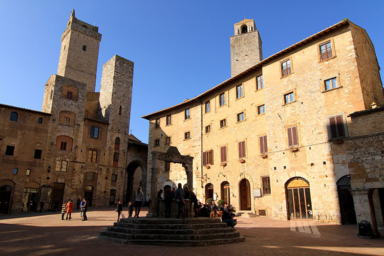 The medieval towers cast shadows on the Piazza della Cisterna in the center of San Gimignano