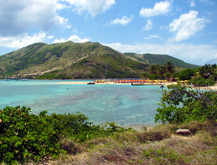 Looking to the spit of sand with umbrellas for rent on Pinel Island from atop a hill on the island in St. Martin