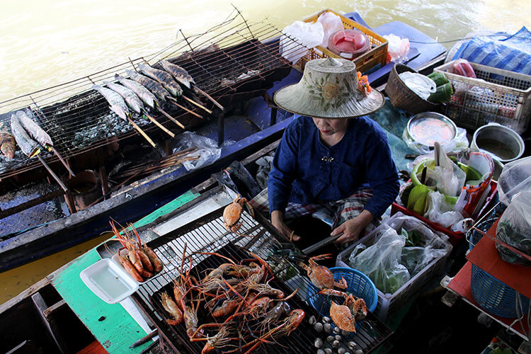 A Thai woman grills lobsters and prawns in her boat and steams blue crabs