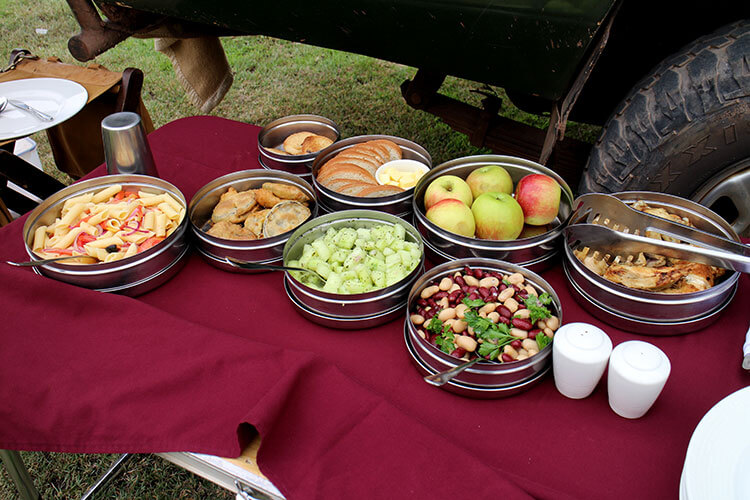 A bush picnic of bean, cucumber and pasta salads, fruit, bread, and roast chicken on SkySafari by Elewana