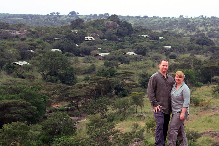 Tim and Jennifer post a top a hill on a bush walk overlooking the luxury tented Serengeti Migration Camp in Tanzania