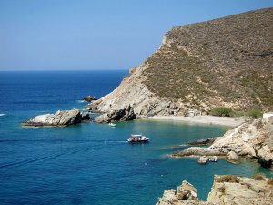View from the cliff above Agios Nikolaos Beach with a small boat crossing to the beach