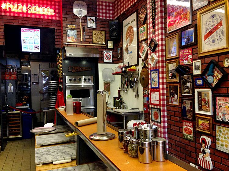 The interior of Pizza School NYC decorated with posters and memorabilia all over the kitchen walls