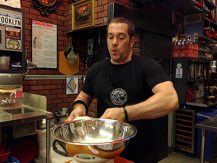 Mark measures some flour into a mixing bowl as he demonstrates how to make pizza dough at Pizza School NYC