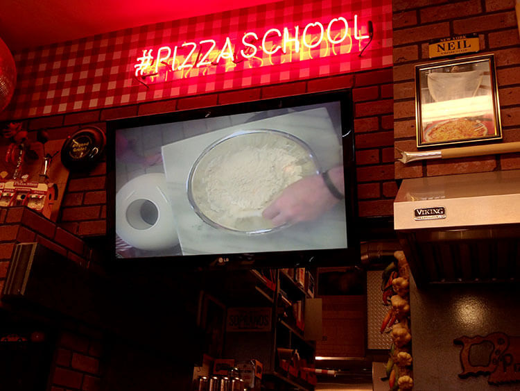 A screen hangs on the wall where you can see the live feed from an overhead camera above the instructor's mixing bowl at Pizza School NYC
