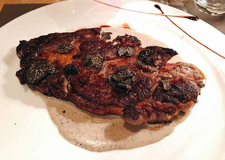 Black truffle shaved on top of a beef steak