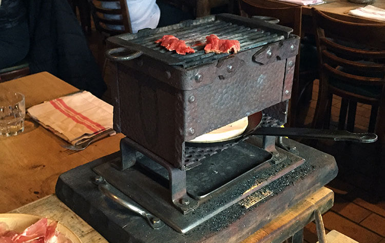 A table top grill that melts the Reblochon cheese in a pan and cooks meat on the griddle top