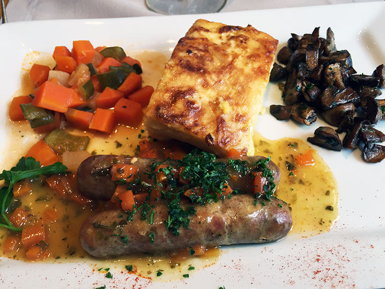 A dish of two sausages typical of Savoie with potatoes, mushrooms and carrots 