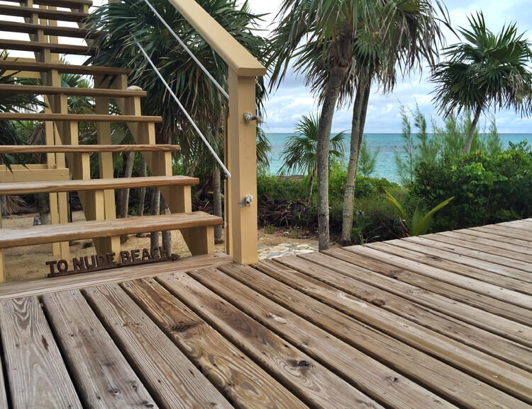 A sign is on the deck and reads "to nude beach" at Sandy Toes Rose Island, Bahamas