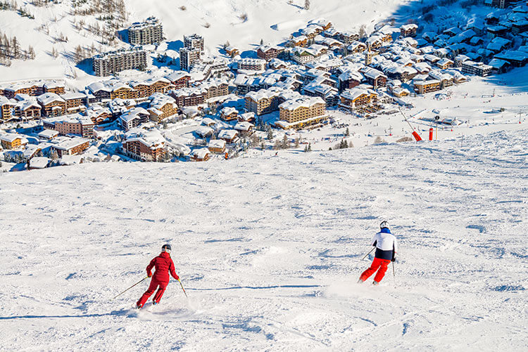 Two skiers ski down toward the town in Val d'Isère, France