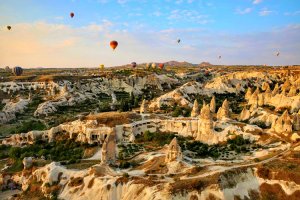Sunrise at Cappadodica with fairy chimneys dotting the landscape and more than 100 hot air balloons in the sky