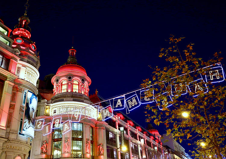 Exterior of Printemps department store in Paris decorated in red, white and green Christmas lights