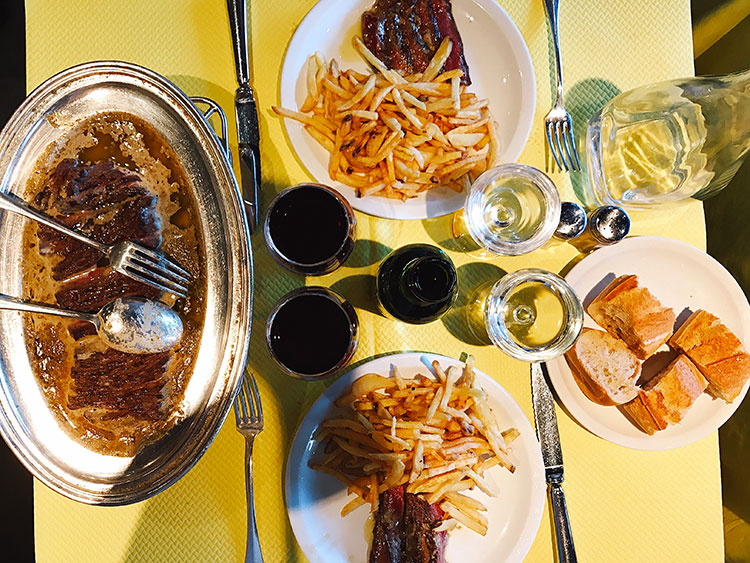 The sliced steak served in the secret sauce with fries and wine at L'Entrecôte Bordeaux