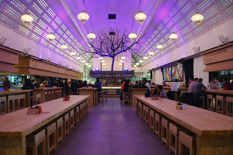 Inside La Boca FoodCourt, which has a tree growing from the central cocktail bar, long rows of communal tables and is lined with specialty restaurants along both sides