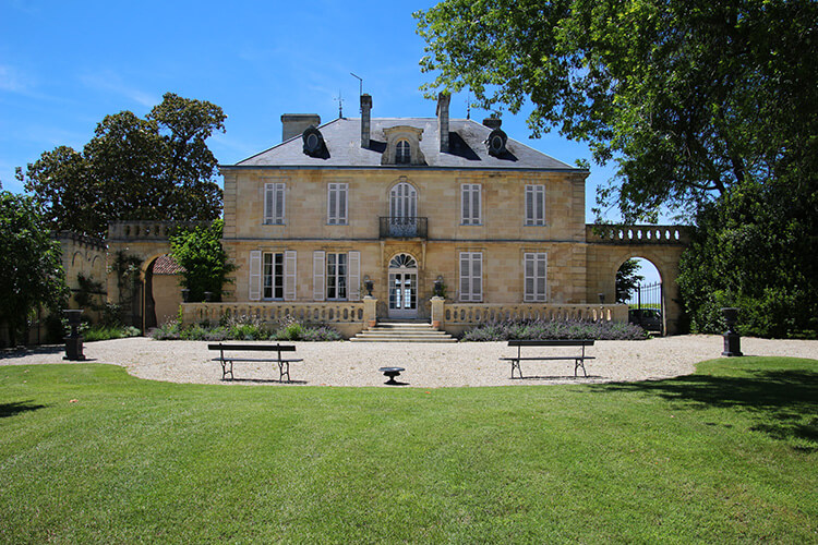 The main house of Chateau Kirwan with a park and benches looking at it