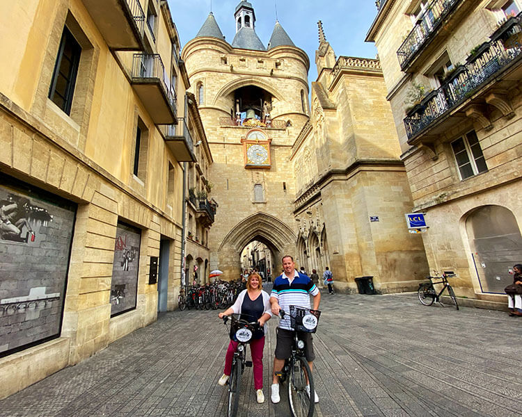 Дженнифер и Тим позируют на велосипедах перед Гросс-Клош в Бордо, Франция.