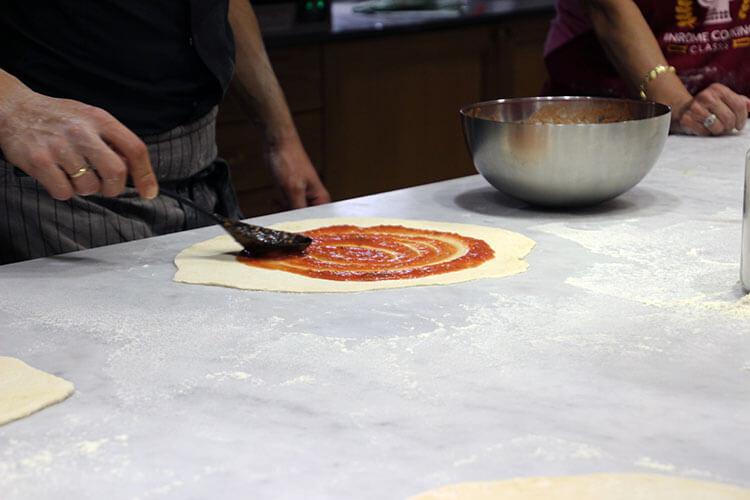 Spreading sauce on the pizza dough