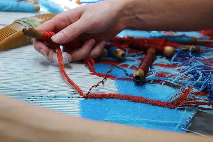 The artists fingers are stained blue from working with the wool