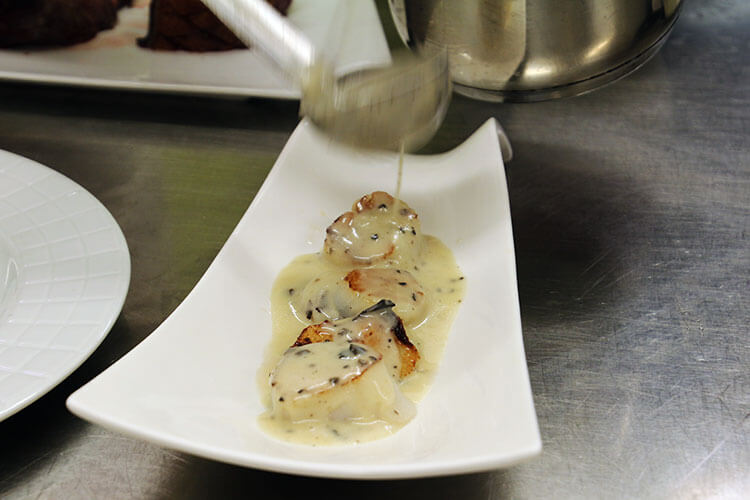 Truffle stuffed scallops are drizzled with a truffle cream sauce