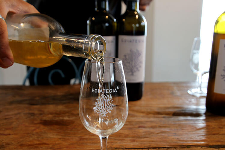 Pouring white Egiategia into a wine glass for the tasting