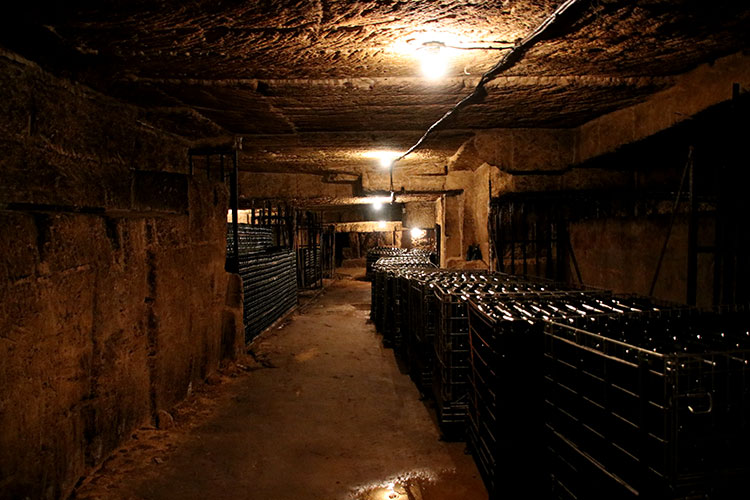Bottles shelved in baskets line the tunnles of the underground quarry at Château de Bonhoste
