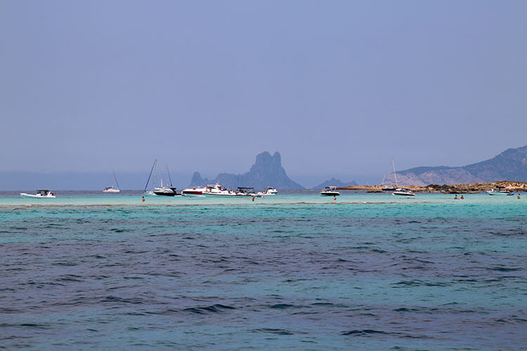 The sandbar linking Formentera and s'Espalmador is uncovered at low tide and people are wading across