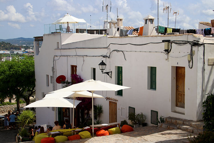 A cafe uses the stairs as seating with colorful beanbags and laundry is strung across the rooftop