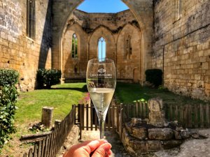 A glass of white Crémant de Bordeaux with the roofless ruined church of Les Cordeliers in the background