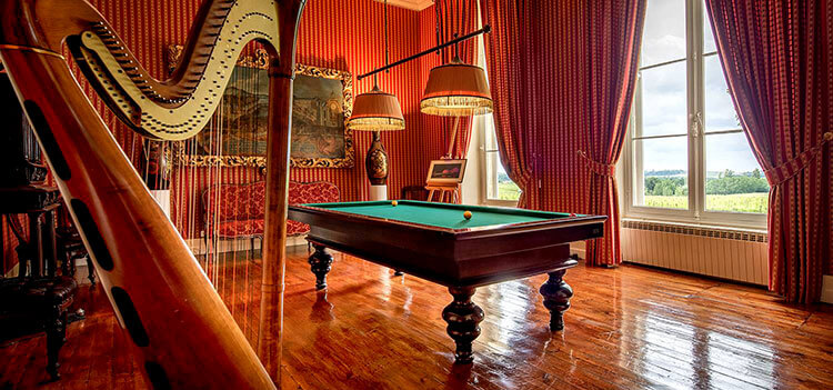 A harp and the pool table in the billards room at Château Fombrauge