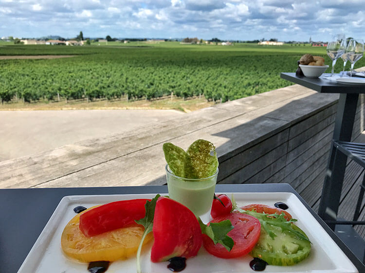 A yellow, red and green tomato salad with the vineyard view blurred behind at La Terrasse Rouge
