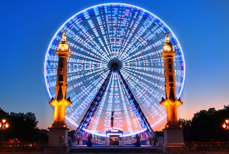 A ferris wheel all lit up at sunset on Place des Quinconces