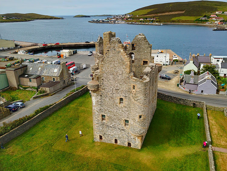 A drone shot of Scalloway Castle with the harbor behind 