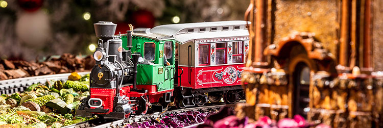 A holiday themed model train in red, white and green on the track at the Holiday Train Show at the New York Botanical Garden