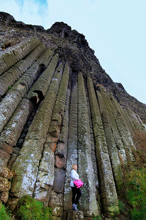 Jennifer poses under the tall basalt columns known as the Organ at Giant's Causeway
