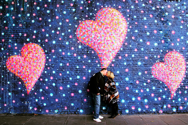 Jennifer and Tim kissing in front of a heart mural near Borough Market in London