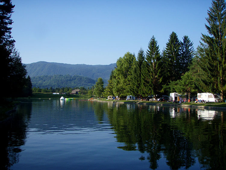 View of the Camping Sobec campsite with some tents pitched and RVs parked along the Sava River in Slovenia