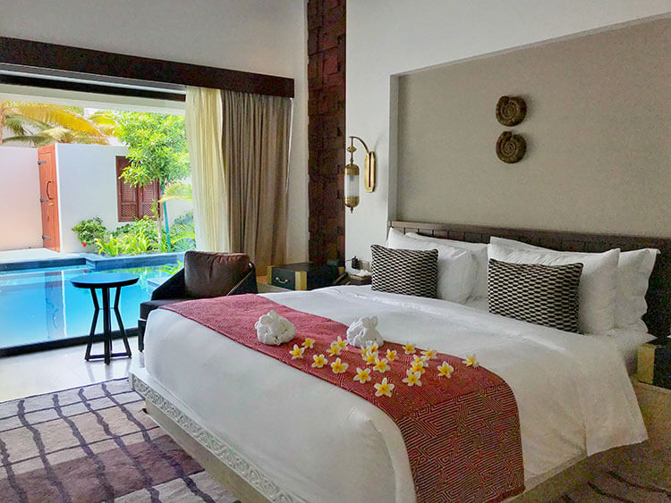 Our 1-bedroom pool villa bedroom with floor to ceiling window looking out to our private plunge pool and garden