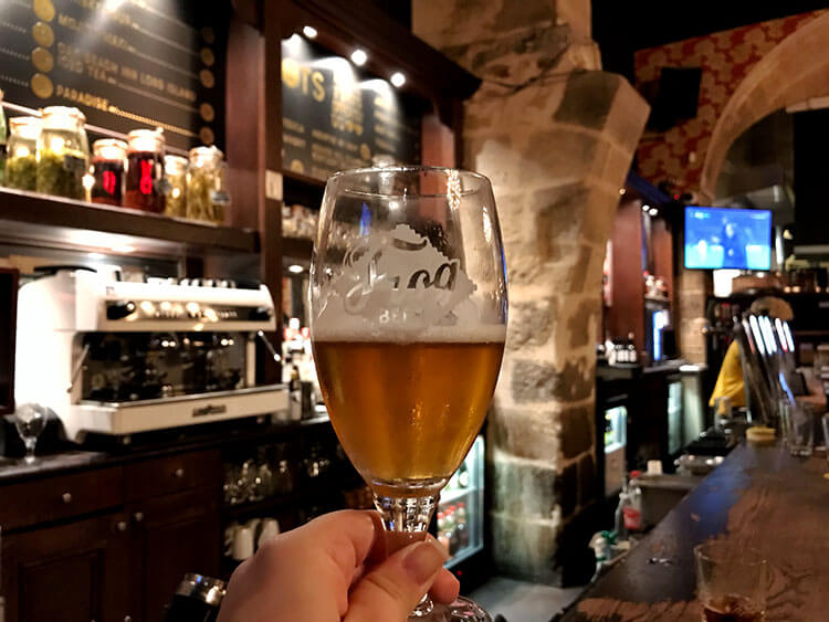 Jennifer holding up a Frog beer in the bar area at the Frog & Rosbif Bordeaux 