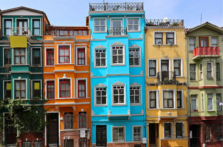 A row of five colorful houses in green, orange, blue, yellow, and mint green in the Balat neighborhood in Istanbul 