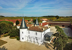 A drone aerial of Château de Seguin's main house with its gray topped towers